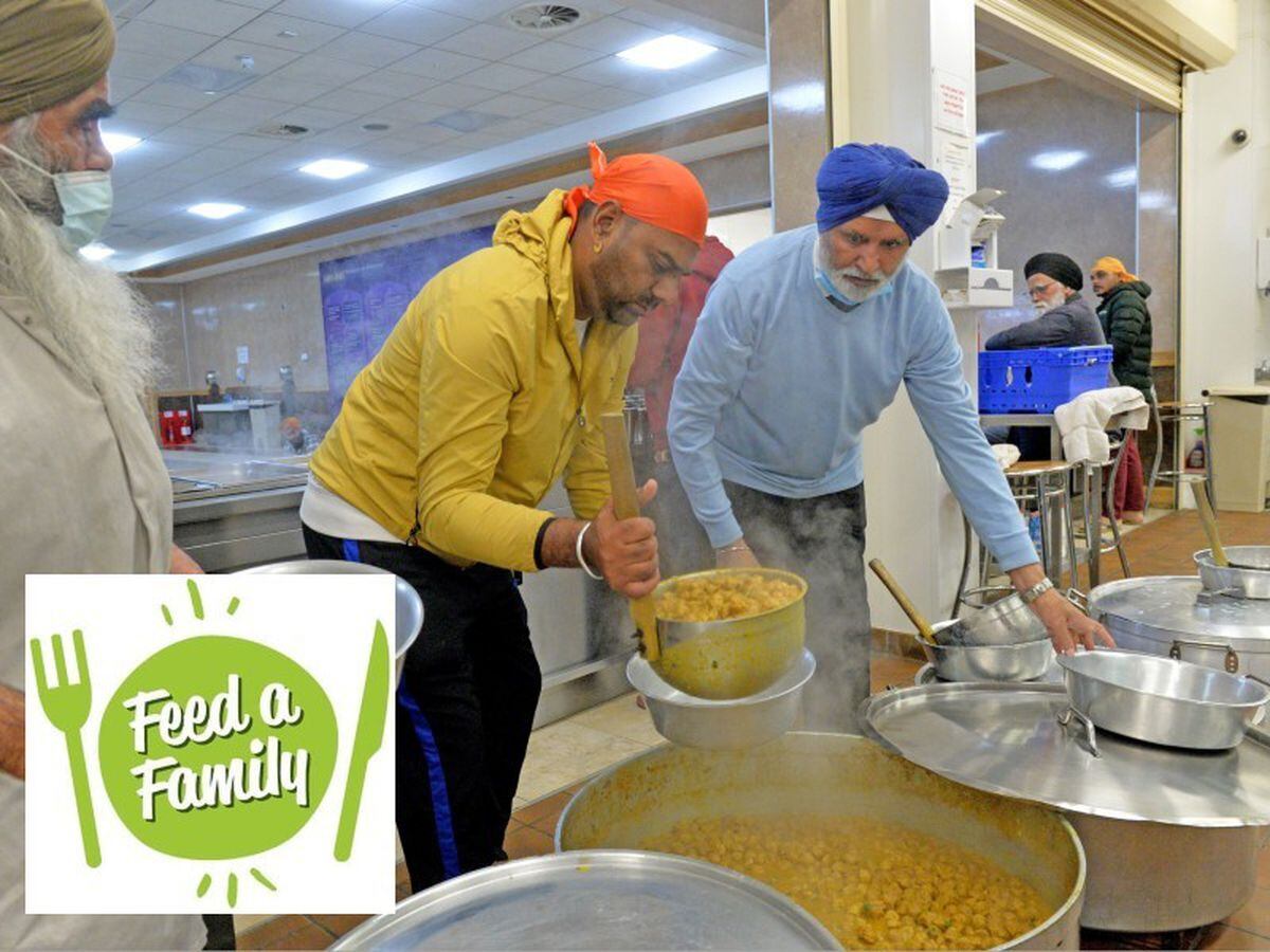 A cook in a Sikh kitchen cooking in an extremely large pot.