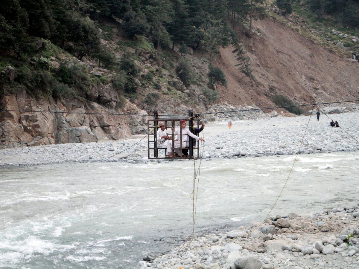 People cross the river on suspended cradles in the Kalam Valley in northern Pakistan