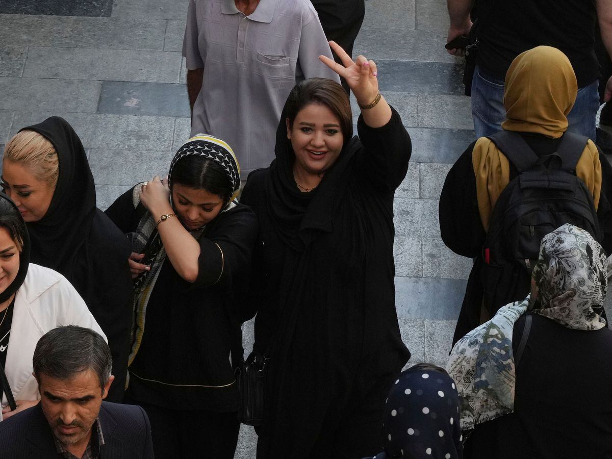 A woman flashes a victory sign as she walks through the old main bazaar in Tehran