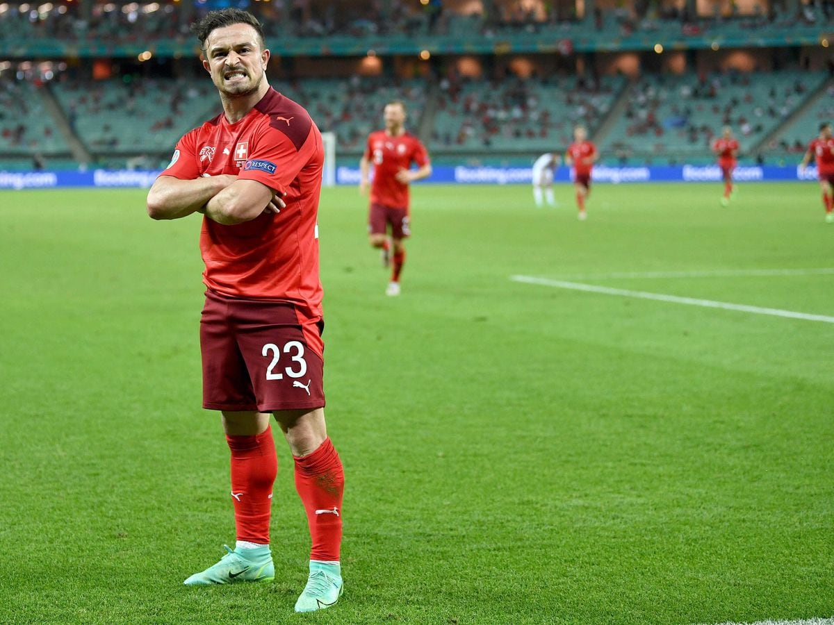  Xherdan Shaqiri wearing the red Swiss national team uniform, looking at the camera with his arms crossed.