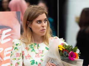 Princess Beatrice holds a bouquet of flowers as she visits a school with British Skin Foundation