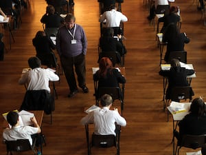 Pupils sat at desks for an exam in a hall