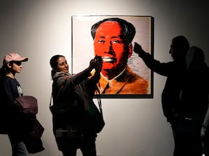 People take snap shots next to China’s late leader Mao Zedong painting by American artist Andy Warhol