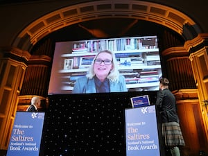 Laura Cummings shown on a big screen while two people look on