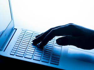 A woman's hand pressing the keys of a laptop keyboard