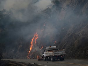 An emergency vehicle clears debris from a road as crews battle the Franklin Fire