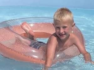 Freddie Farrow smiles as he plays with a rubber ring in a swimming pool