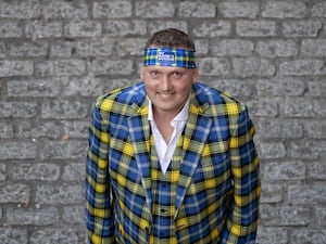 Doddie Weir smiling while dressed in a yellow and blue tartan suit and bandana