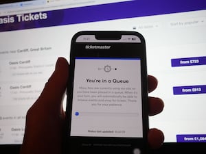 A person in a queue to access the Ticketmaster website on their phone, with the StubHub website in the background