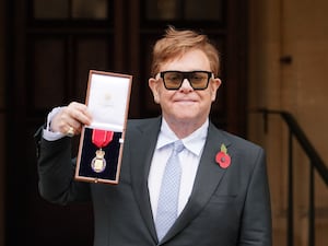 Sir Elton John holding up a medal