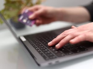 A woman using a laptop as she holds a bank card