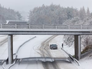 A person stands next to his vehicle on an empty snow covered M9 motorway near Stirling