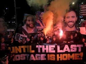 Demonstrators light flares and hold banners as they gather during a protest calling for the release of all hostages held captive by Hamas