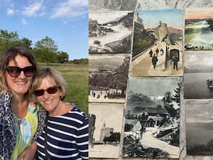 Two women, next to postcards on a table