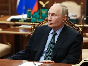 Russian President Vladimir Putin sits behind a desk