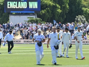 Jacob Bethell and Joe Root lead the teams off following England's the field following their first Test win over New Zealand with the scoreboard in the background