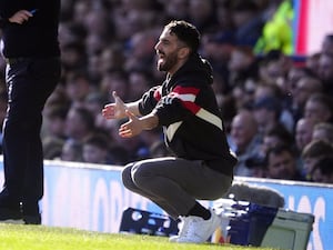 Manchester United manager Ruben Amorim crouches on the touchline as he watches his side at Everton.