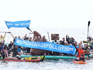 Protesters against sewage pollution hold banners while on the water