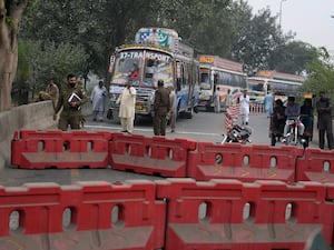 Police officers stand guard on an entry point to motorway leading to Islamabad, which has been closed by authorities due to a planned rally by supporters of imprisoned former Prime Minister Imran Khan’s Pakistan Tehreek-e-Insaf party, in Lahor