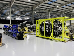 A rocket on its side under construction in a large warehouse