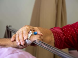 Elderly people holding hands in hospital