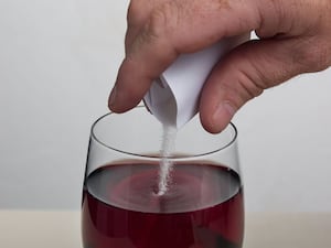 A suspicious powder being poured into a glass of red wine