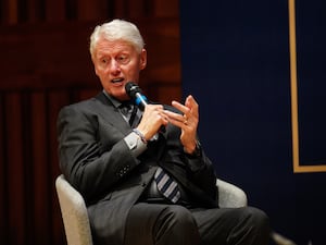 Bill Clinton speaks while sat in a chair