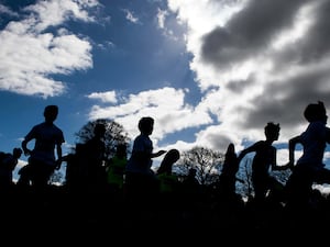 Silhouette of children running against a cloudy sky