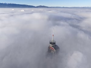 A tall building peaks through a dense layer of fog and smog in Sarajevo, Bosnia