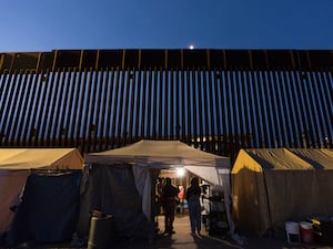 Volunteers talk in a tent along a border wall separating Mexico from the US