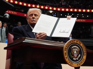 US President Donald Trump signs an executive order as he attends an indoor Presidential Inauguration parade event at Capital One Arena in Washington