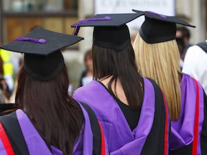 The backs of three students in graduation hats and gowns