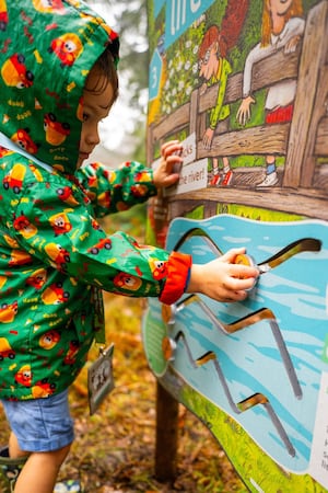 A young child playing with an interactive panel on the new Stick Man trail