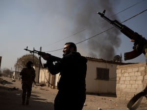 Syrian fighters aim their weapons in direction of suspected looters at a residential complex of former Bashar Assad’s military officers at the village of Husseiniyeh, in the outskirts of Damascus, Syria