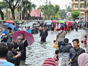 Residents walk along a flooded street in Malaysia