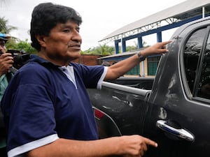 Evo Morales next to a car with bullet holes on it