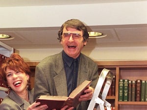 Kathy Lette and David Lodge having a laugh on a ladder, with a book, in a library