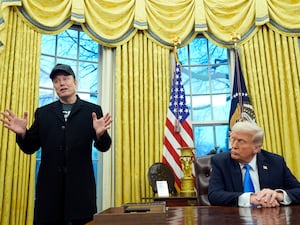 President Donald Trump listens as Elon Musk speaks in the Oval Office