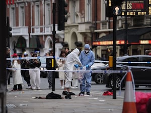 Forensic investigators collect evidence at the scene on Shaftesbury Avenue (PA)