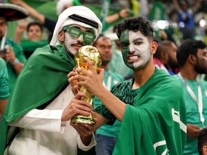 Saudi Arabian fans pose with a replica World Cup trophy at a match against Mexico at the 2022 finals