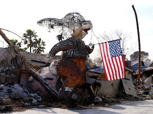 An American flag is suspended from a charred bunny sculpture at the Bunny Museum, which was destroyed by the Eaton Fire in Altadena