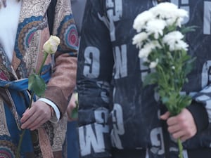 Students hold white flowers in front of the court building as the verdict is given in a trial of the parents of a boy who killed 10 people in a school shooting in 2023 in Belgrade