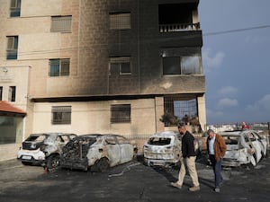 Palestinians inspect vehicles that were burned