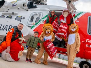 Santa, lion helpers, a Coast Guard member and an elf drop off sacks of toys at a hospital from e helicopter