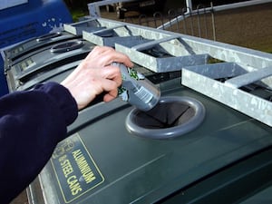 A stock picture of someone recycling cans