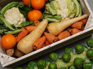 A crate of fresh fruit and vegetables, including carrots, cauliflower, parsnips, Brussel sprouts, apples, and oranges