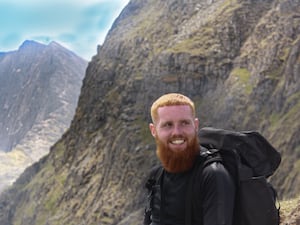 Russ Cook wearing black rucksack while stood by a mountain