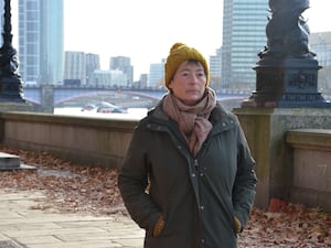 Clare Turner standing by a wall along the Thames