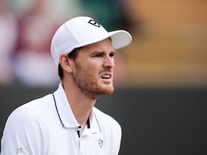 Jamie Murray wearing a peaked cap and playing tennis