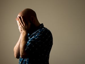 A man holdings his head in his hands